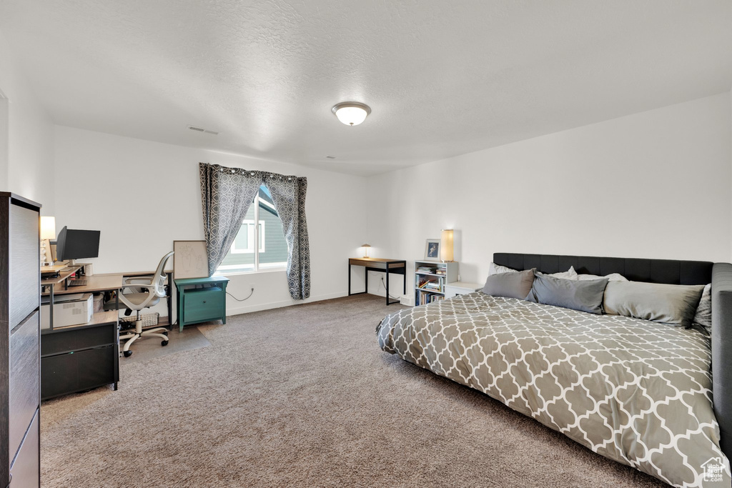 Carpeted bedroom with a desk and baseboards