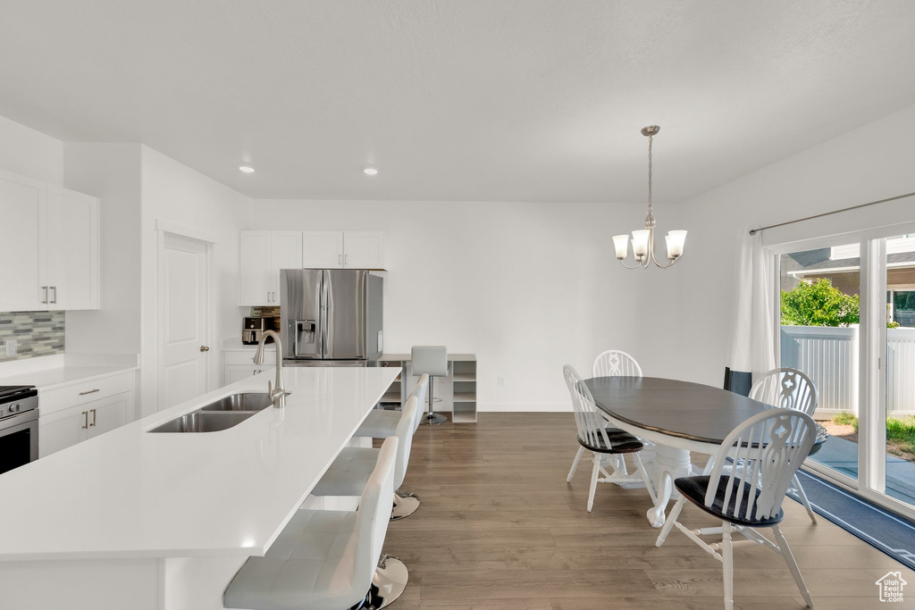 Kitchen featuring stainless steel fridge with ice dispenser, a sink, wood finished floors, a chandelier, and white cabinetry