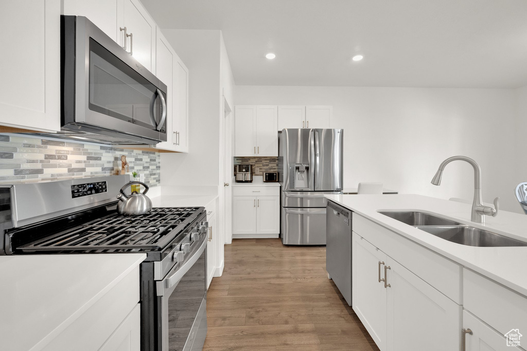 Kitchen with appliances with stainless steel finishes, a sink, white cabinetry, and recessed lighting
