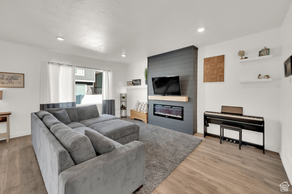 Living room with recessed lighting, light wood finished floors, a fireplace, and baseboards