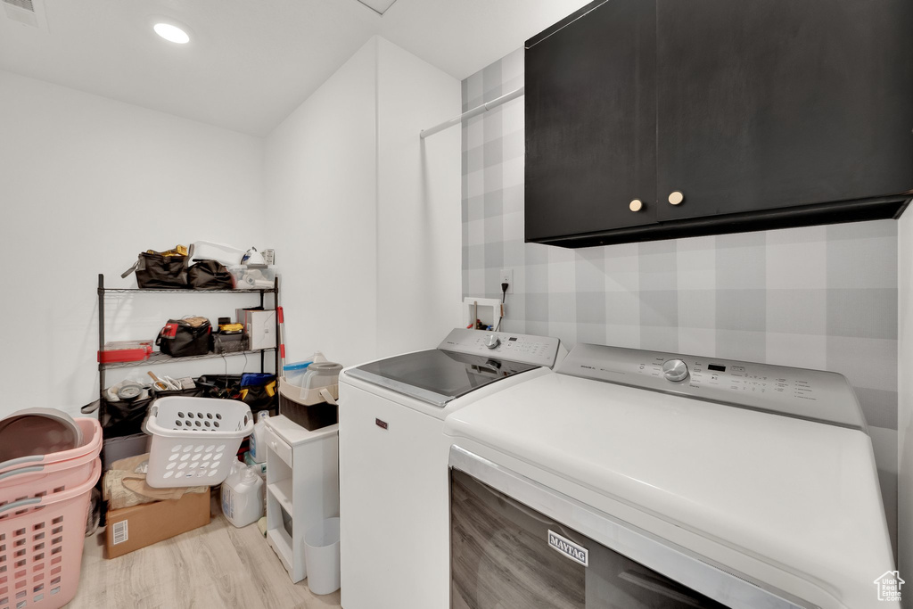 Laundry area featuring cabinet space, washing machine and clothes dryer, light wood-type flooring, and recessed lighting