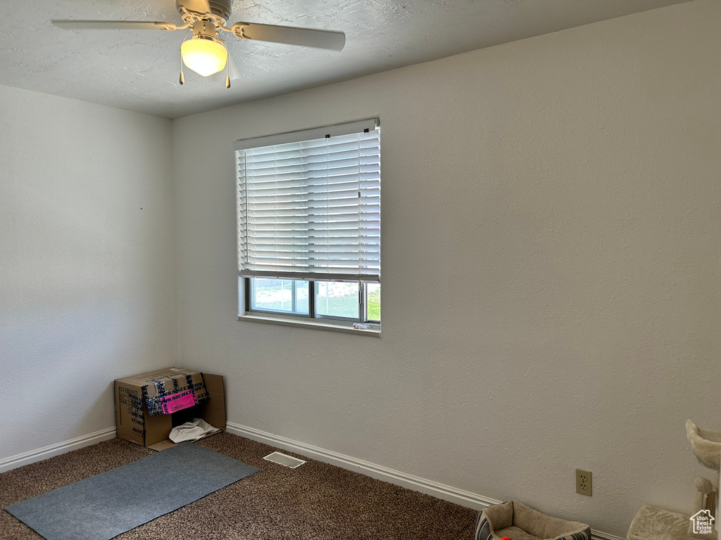 Carpeted spare room with a ceiling fan and baseboards