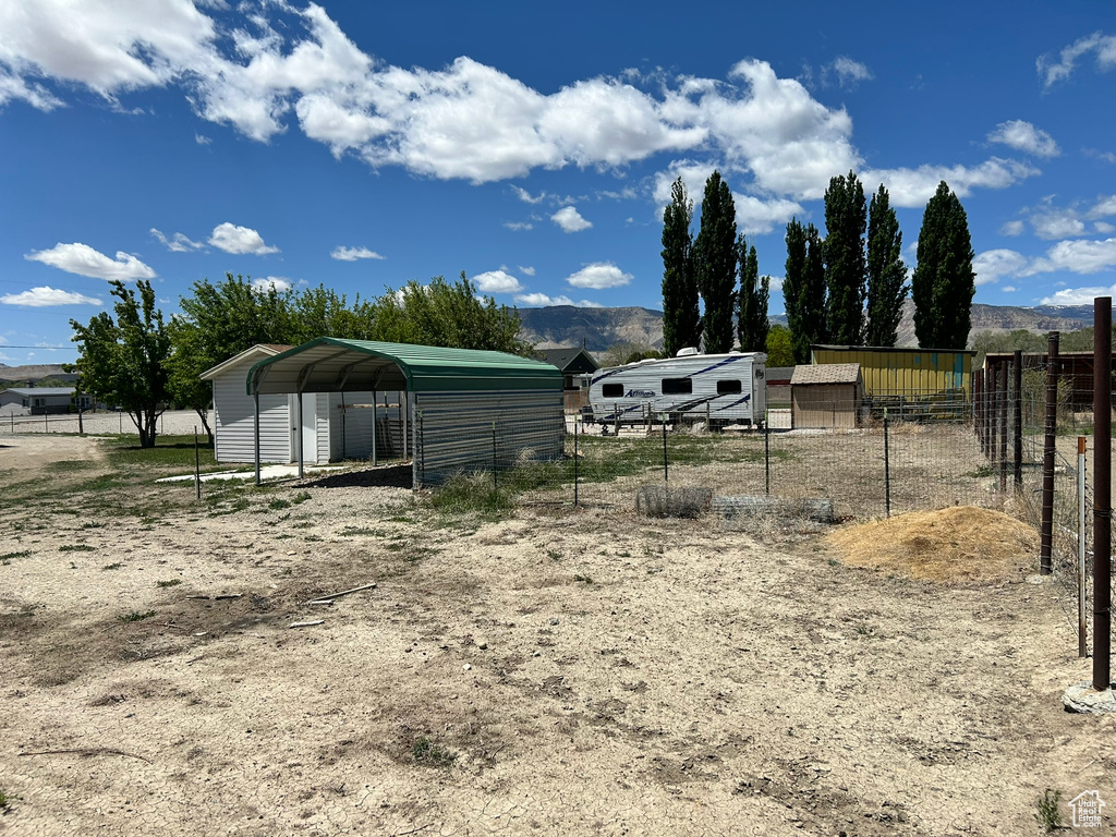 View of yard with a detached carport, an outbuilding, and a mountain view