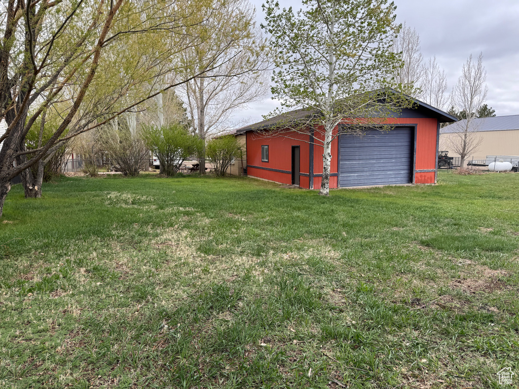 View of grassy yard with an outbuilding and a garage