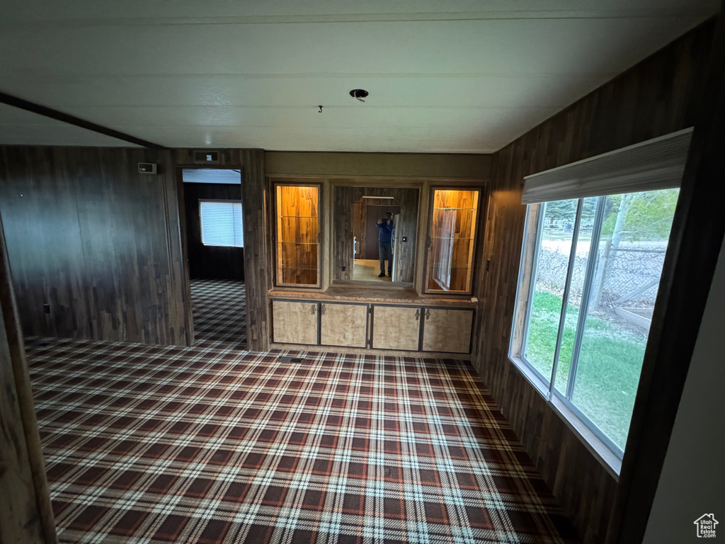 Unfurnished room with wooden walls and carpet flooring