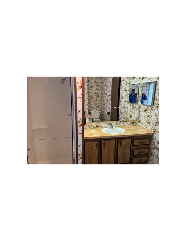 Full bath featuring vanity, a shower, and wallpapered walls