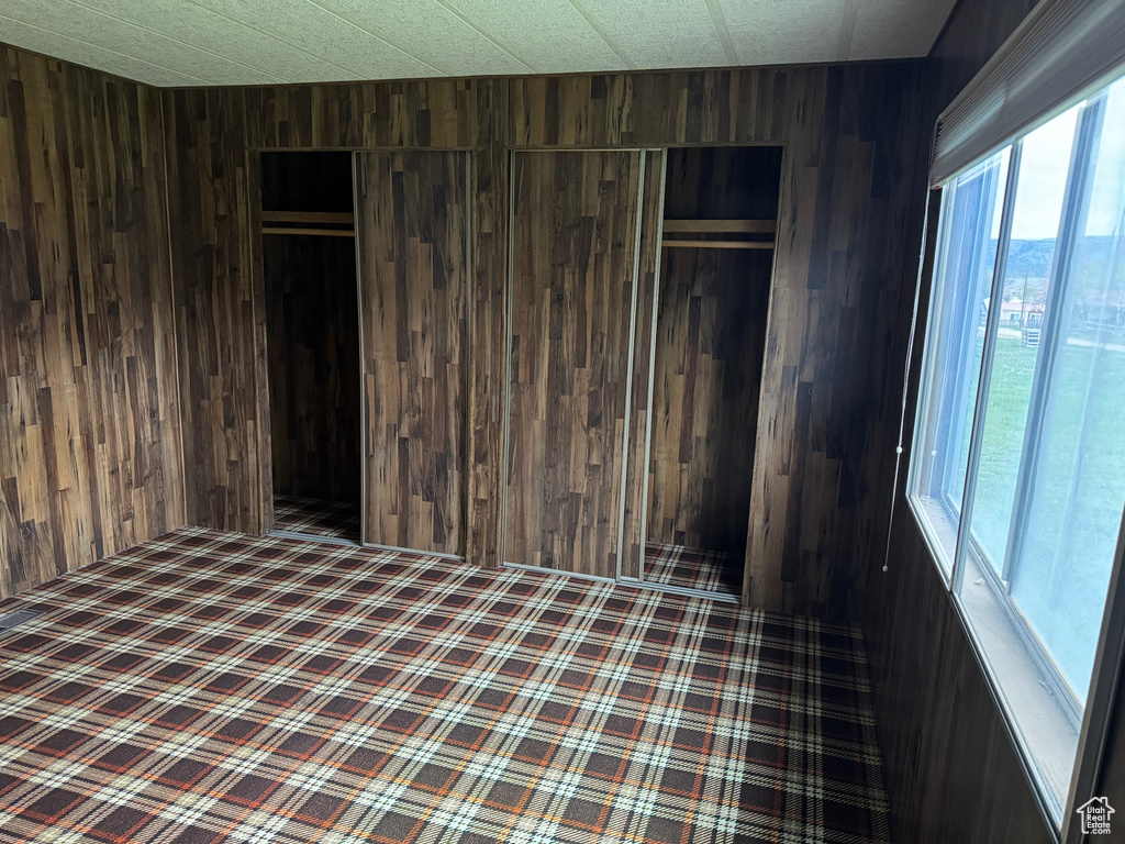Unfurnished bedroom featuring wooden walls and a closet