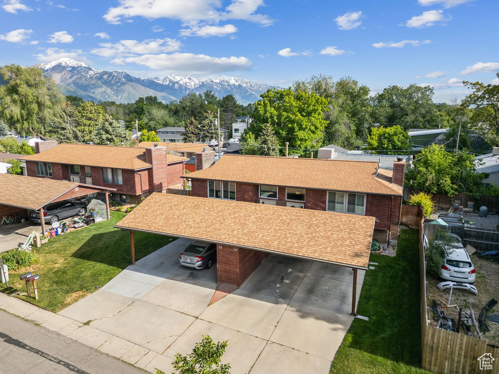 View of front facade featuring a mountain view, a carport, concrete driveway, and a chimney