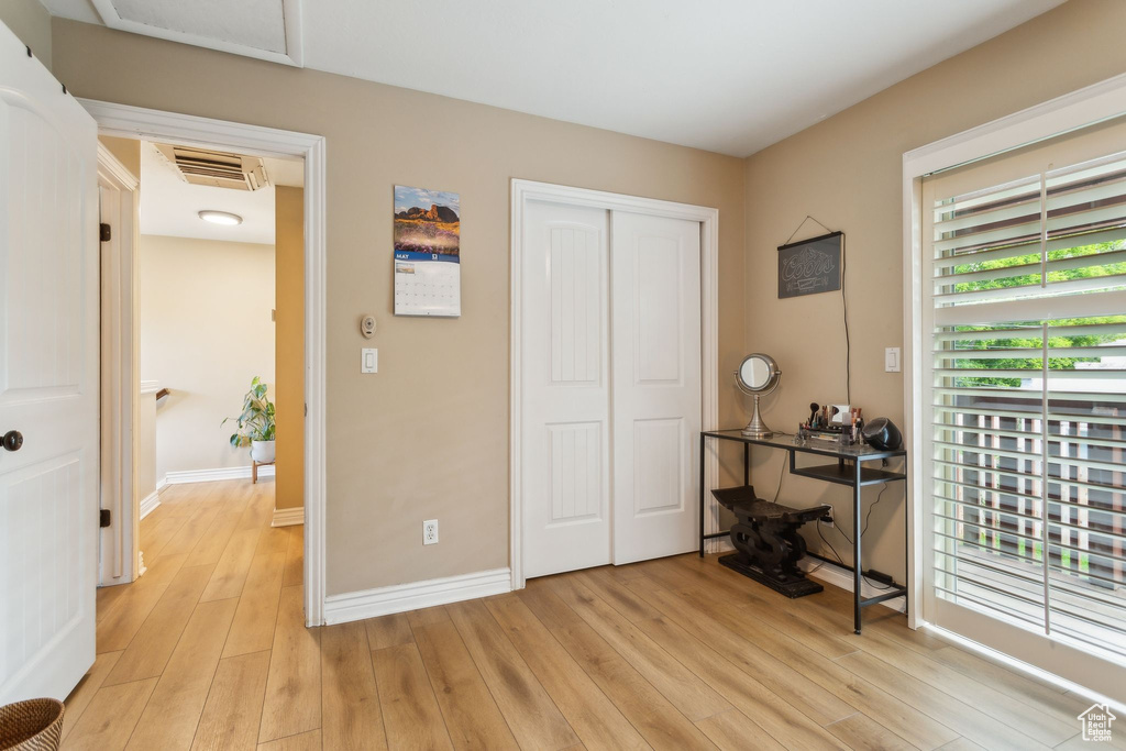 Bedroom with light wood finished floors, a closet, baseboards, and attic access