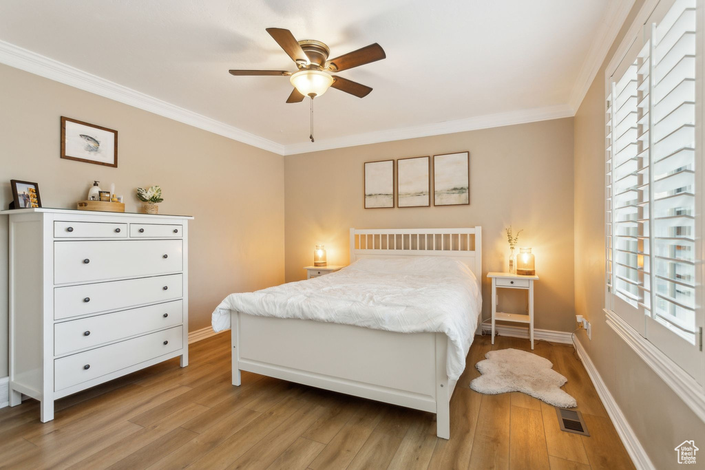 Bedroom with light wood-style floors, crown molding, baseboards, and ceiling fan