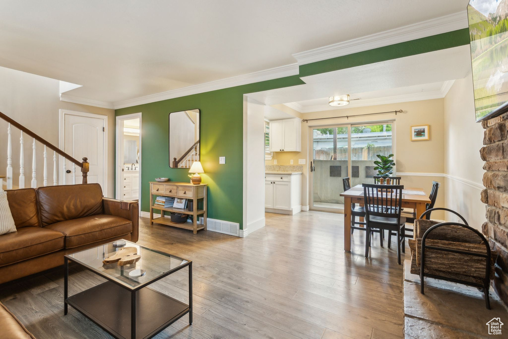 Living area with stairway, light wood finished floors, ornamental molding, and baseboards