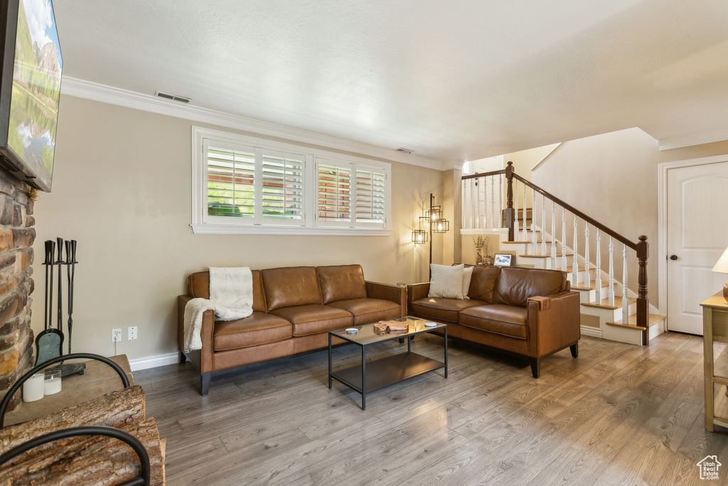 Living room with stairs, wood finished floors, crown molding, and baseboards