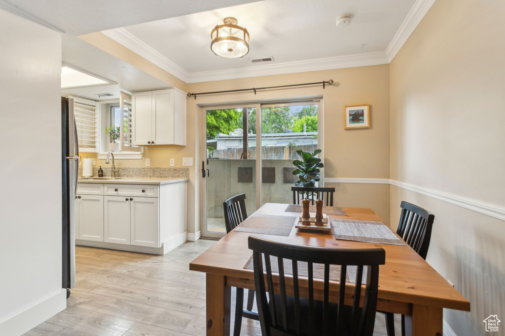 Dining space featuring light wood-style flooring, crown molding, and baseboards