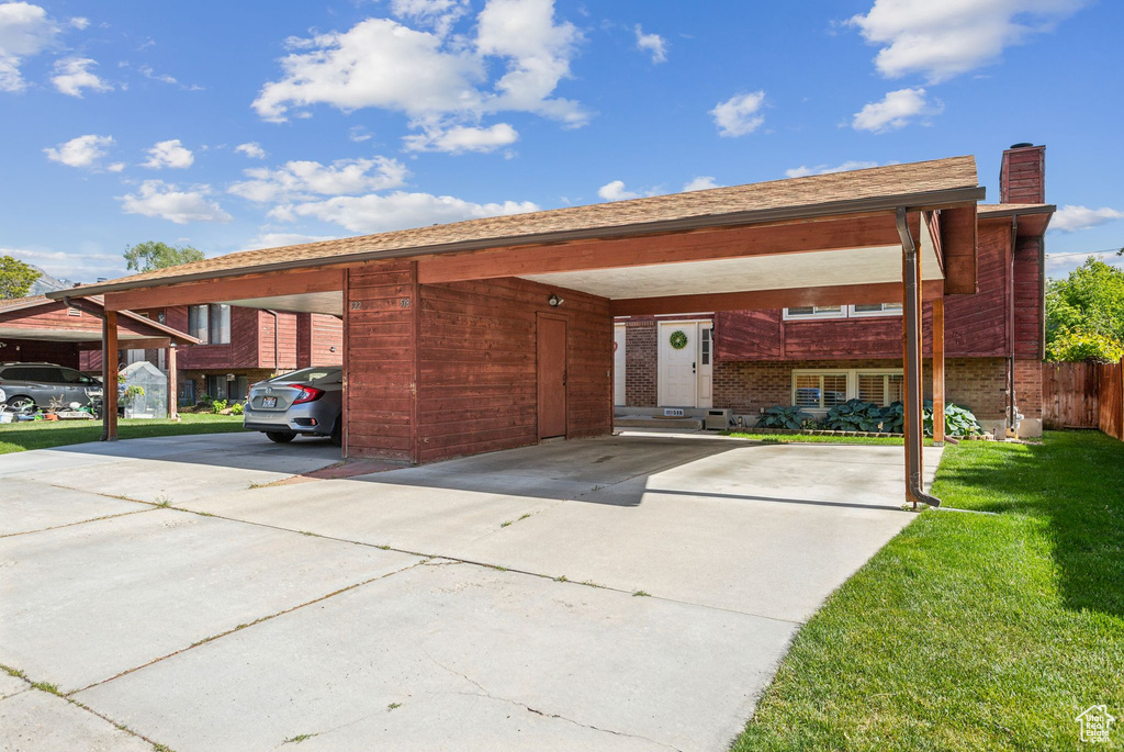 View of front of property featuring driveway, a chimney, and a carport