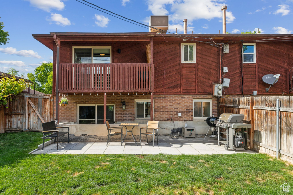 Back of property with a balcony, a patio, and brick siding