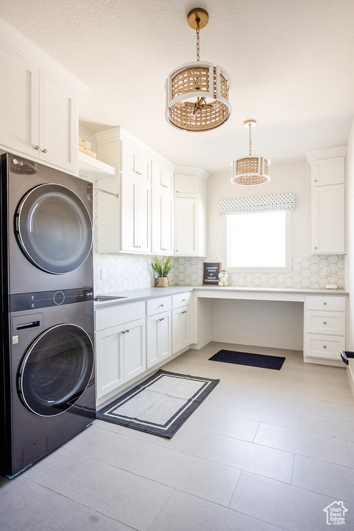 Laundry room with stacked washer and clothes dryer, cabinet space, and an office area