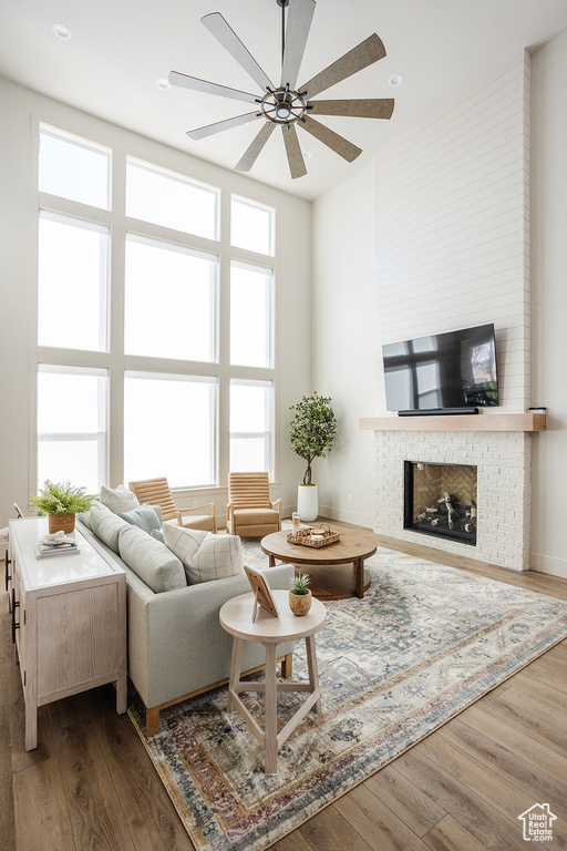 Living area with dark wood finished floors, ceiling fan, a brick fireplace, and recessed lighting