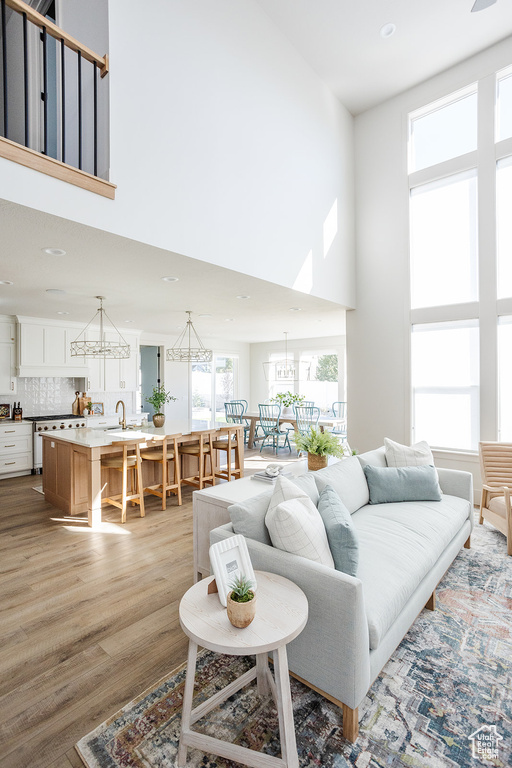 Living room featuring a high ceiling, a chandelier, light wood finished floors, and recessed lighting