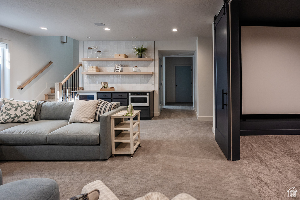 Living area featuring light carpet, a barn door, recessed lighting, and stairs