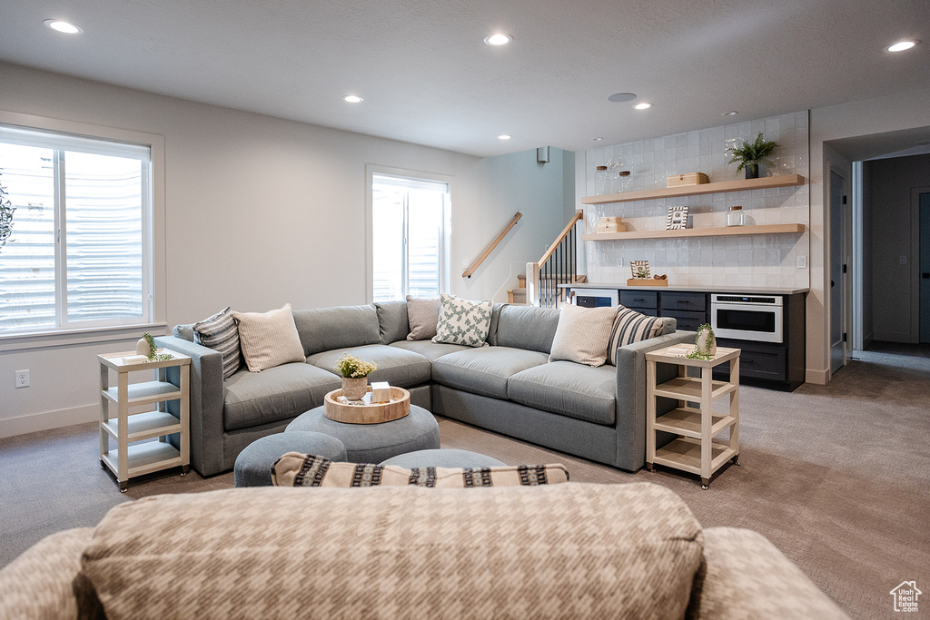 Living room featuring recessed lighting, plenty of natural light, stairway, baseboards, and light carpet
