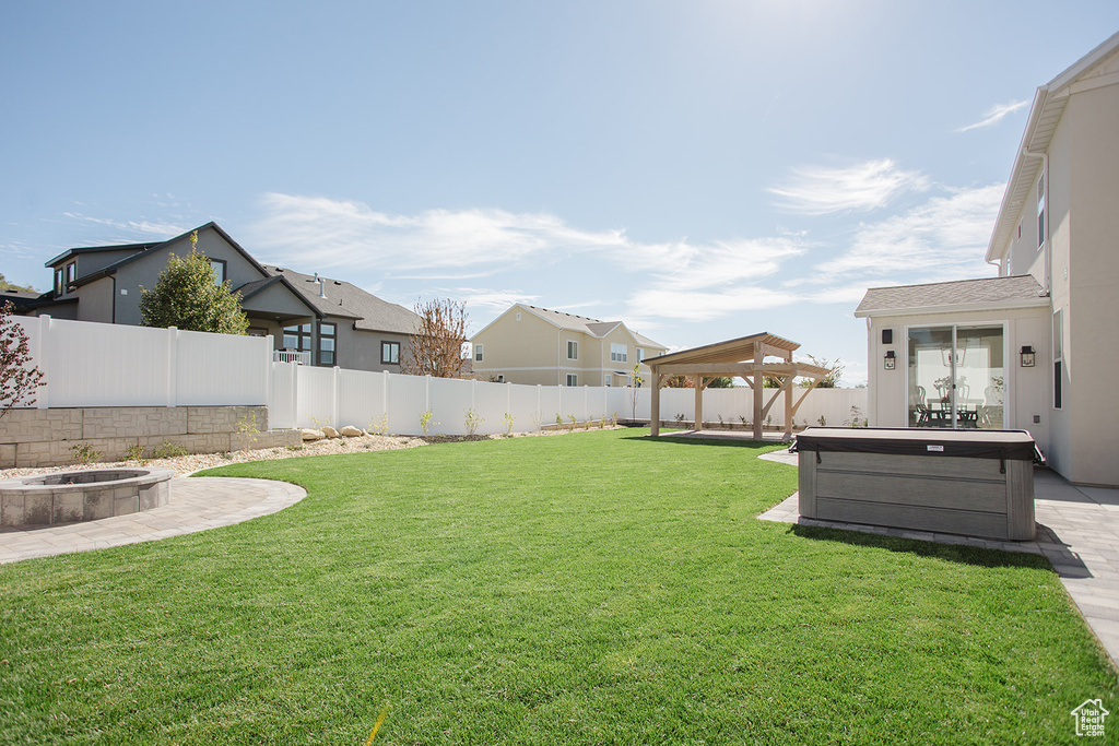 View of yard with a hot tub, a fire pit, a gazebo, a patio area, and a residential view