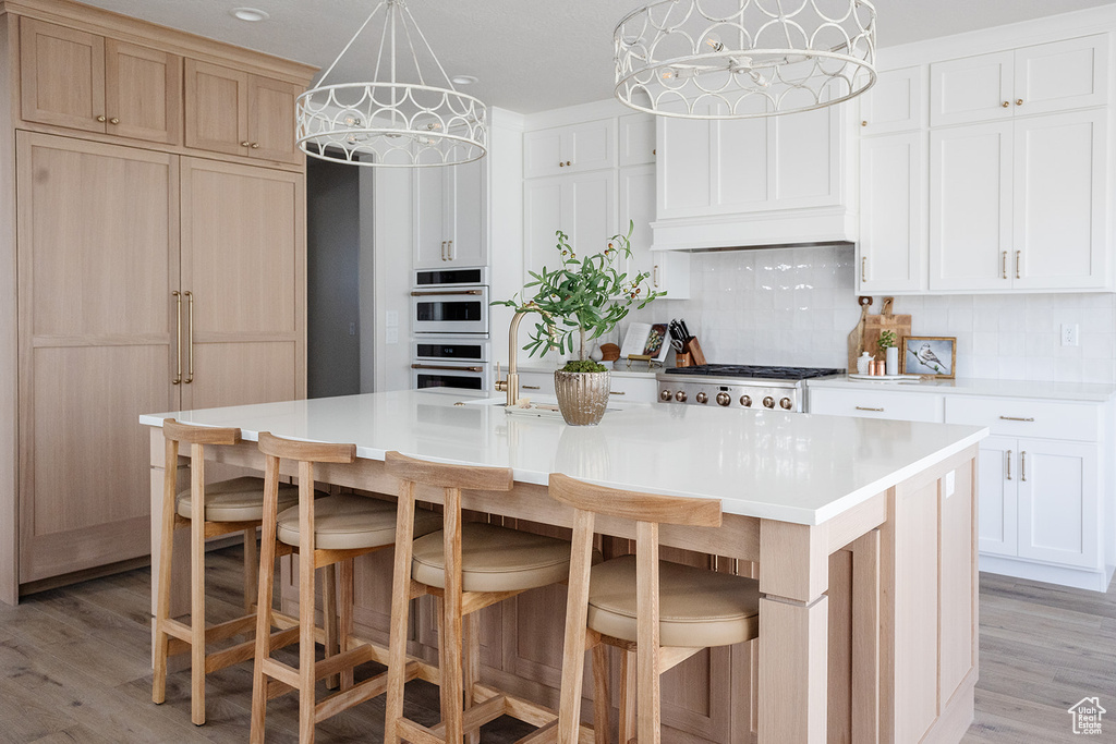 Kitchen with stainless steel gas stovetop, decorative backsplash, light wood-type flooring, and light countertops