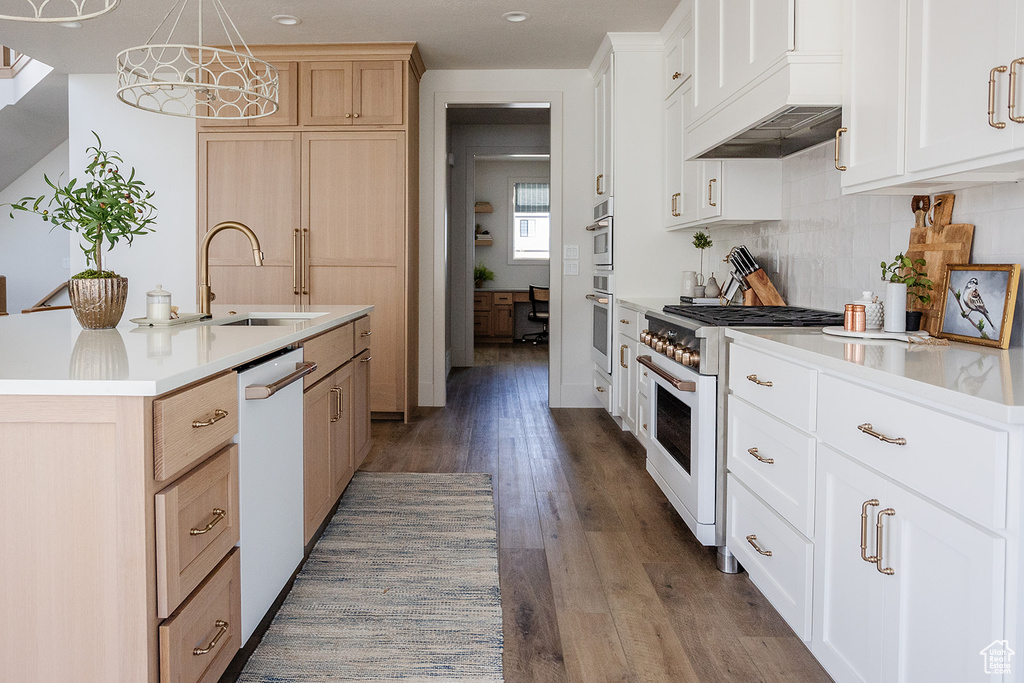 Kitchen with white appliances, a sink, light countertops, wood finished floors, and custom exhaust hood