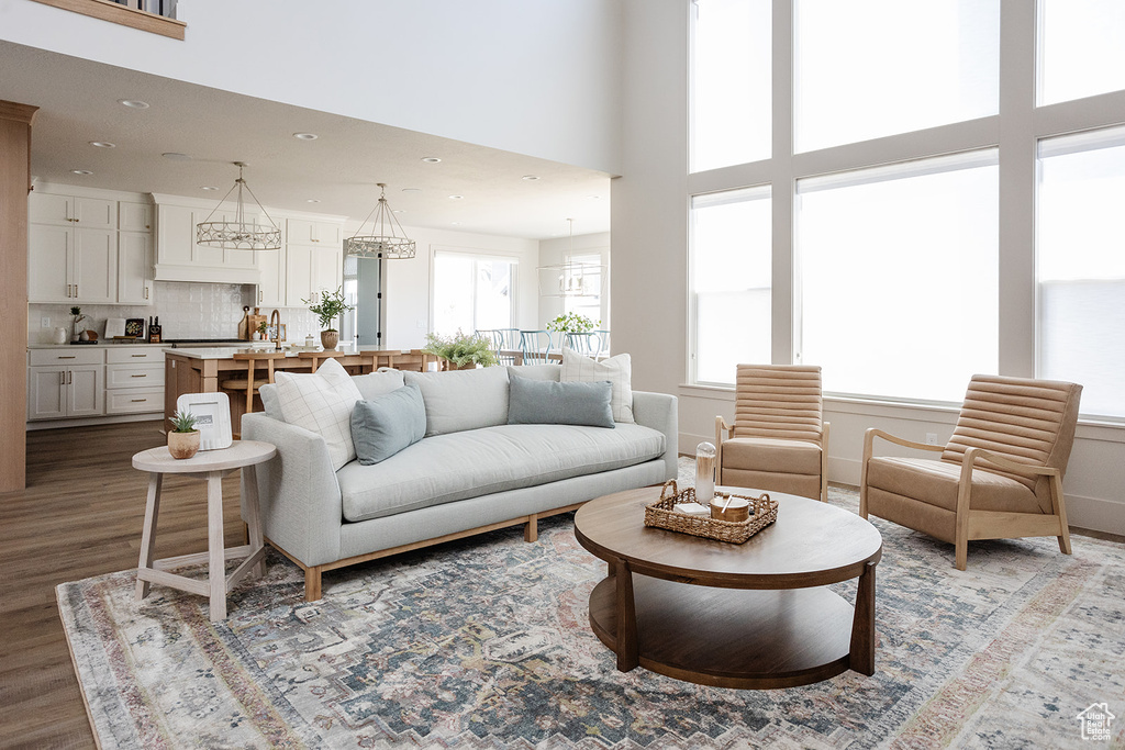 Living room featuring wood finished floors, recessed lighting, a chandelier, and a high ceiling