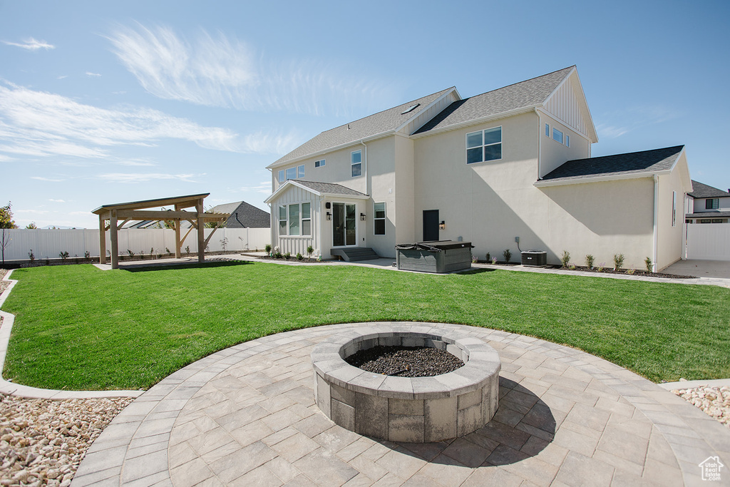 Rear view of house with a patio, an outdoor fire pit, a hot tub, and roof with shingles