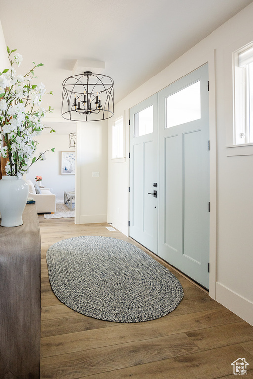 Entryway featuring wood finished floors, a chandelier, and baseboards