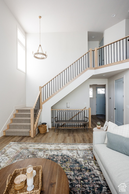 Living area with stairs, wood finished floors, a high ceiling, and baseboards
