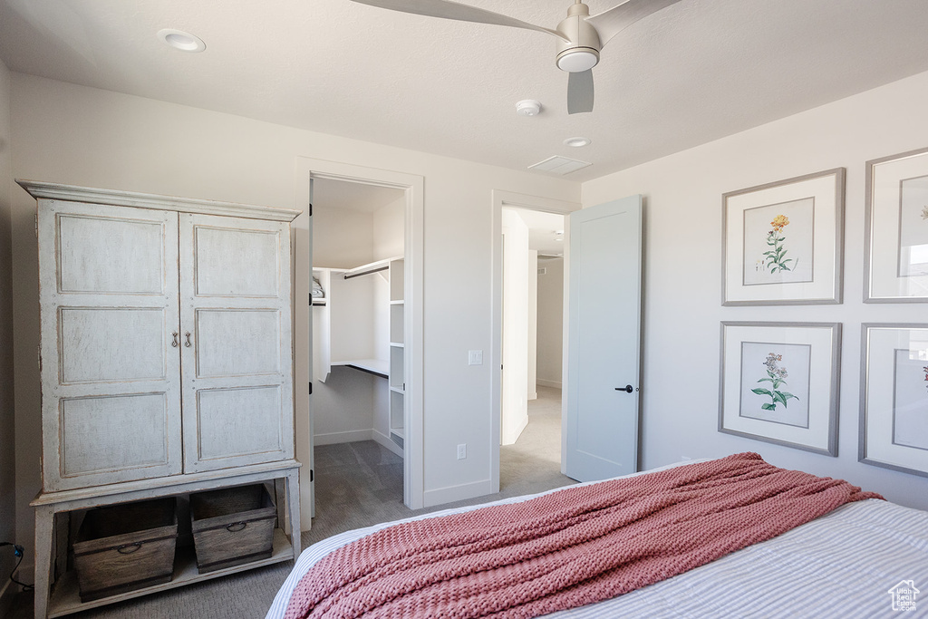Bedroom featuring light carpet, ceiling fan, baseboards, and a spacious closet