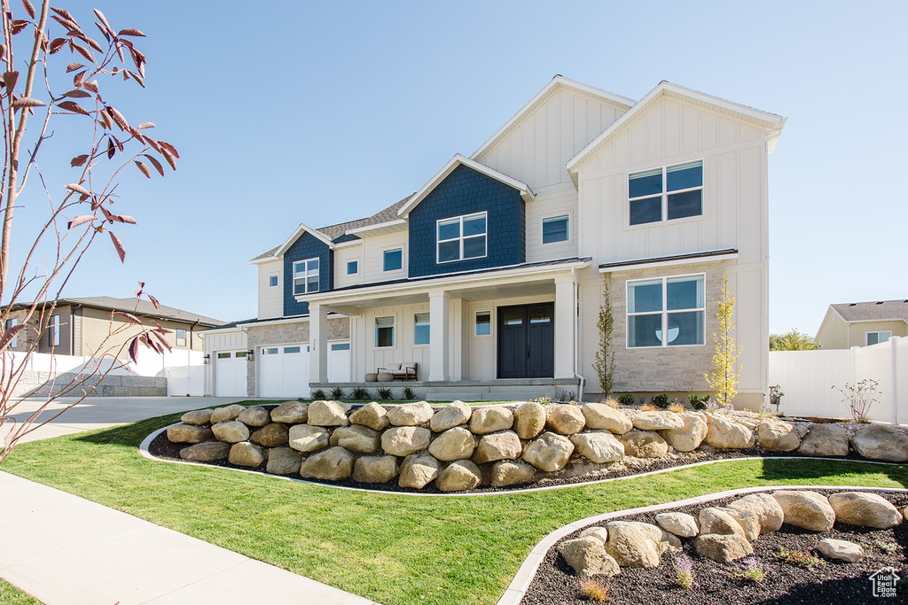 View of front of home with board and batten siding, concrete driveway, a garage, and covered porch