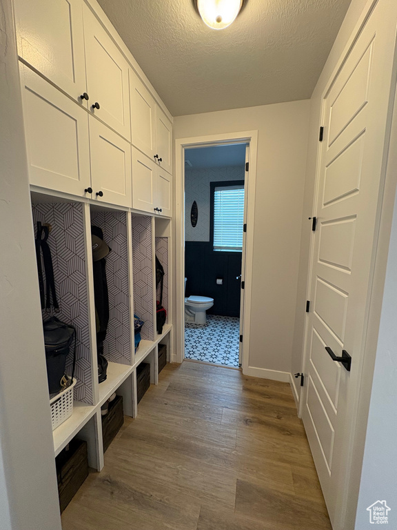 Mudroom featuring wood finished floors, baseboards, and a textured ceiling