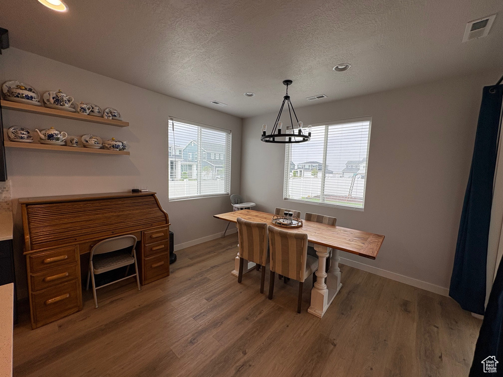 Dining room with wood finished floors, a chandelier, baseboards, a textured ceiling, and recessed lighting