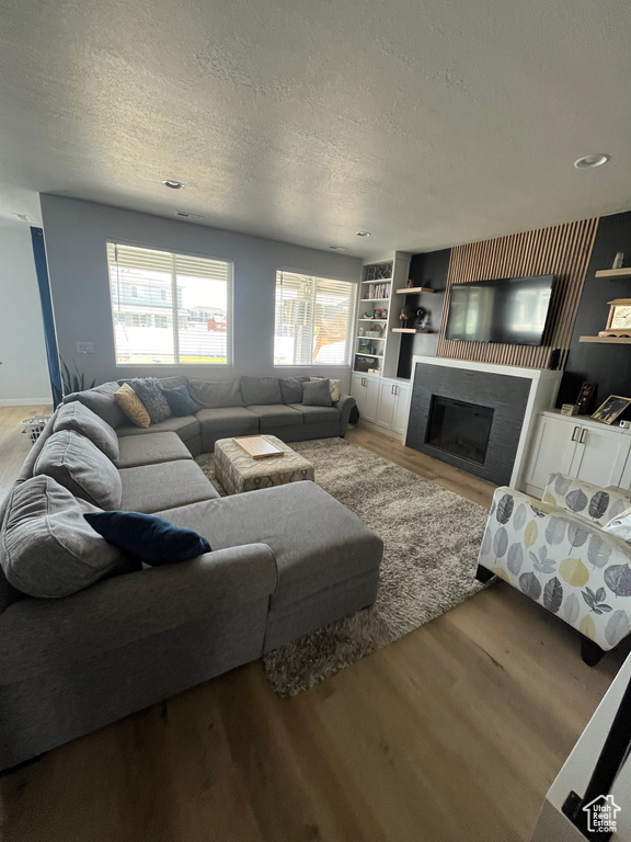 Living area featuring wood finished floors, a textured ceiling, and a fireplace
