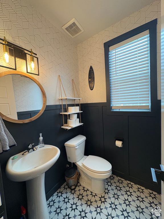 Bathroom featuring wallpapered walls, a wainscoted wall, toilet, and tile patterned floors