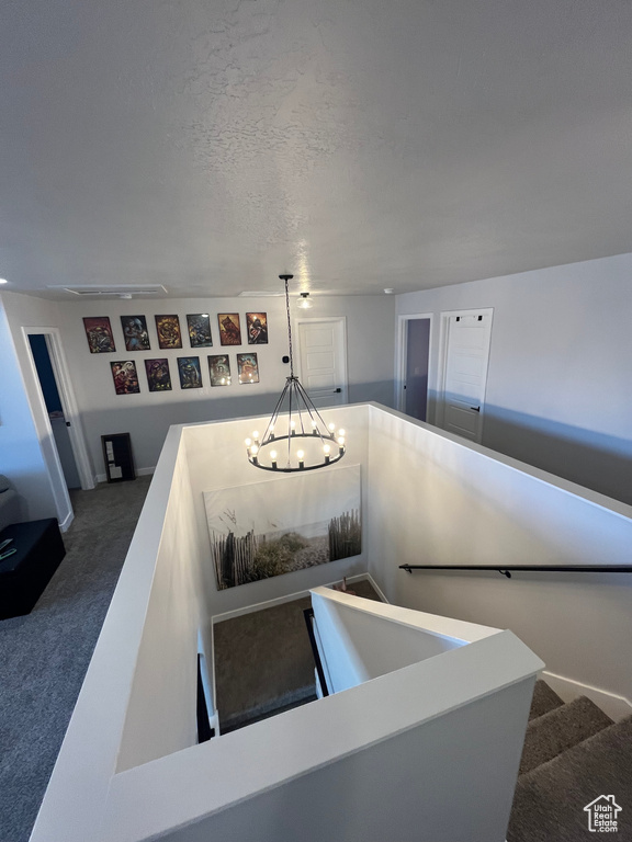 Stairway with a chandelier and carpet flooring