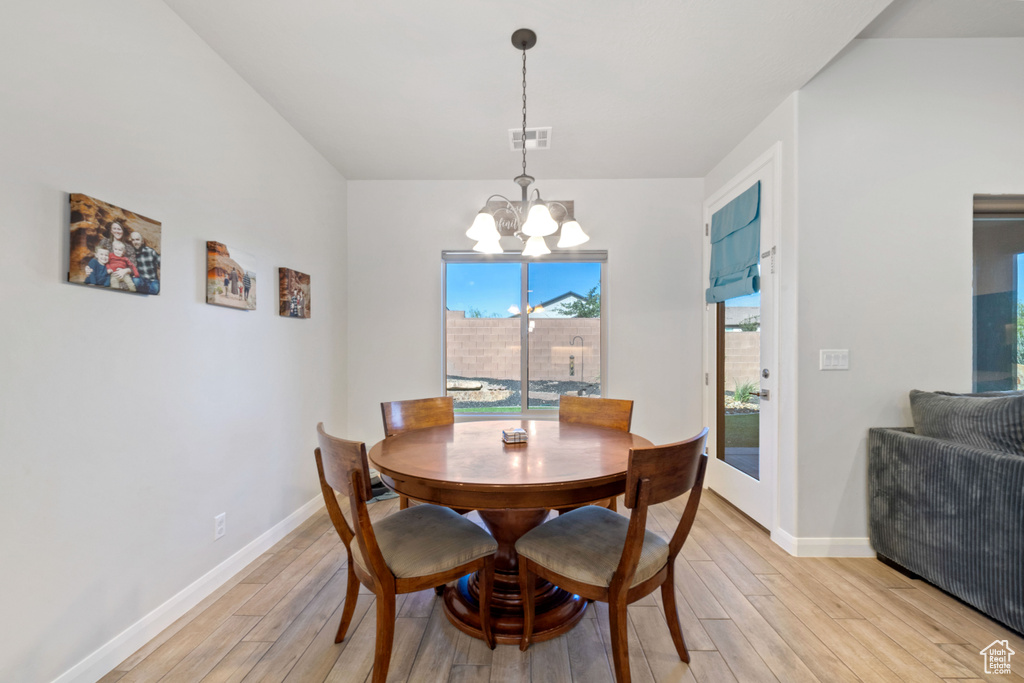Dining area with a chandelier, light wood-style floors, and baseboards