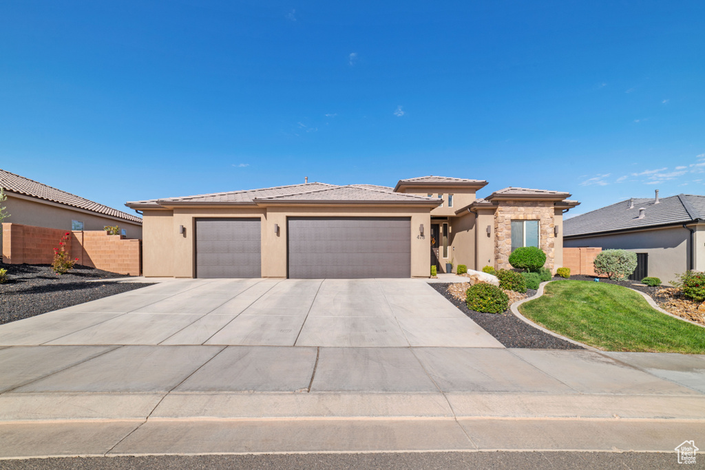 Prairie-style home featuring a garage, driveway, a tile roof, and stucco siding