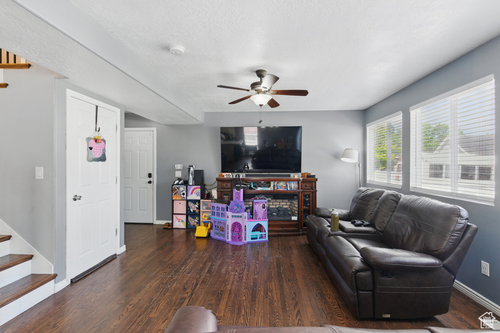 Living area featuring wood finished floors, ceiling fan, baseboards, and stairway