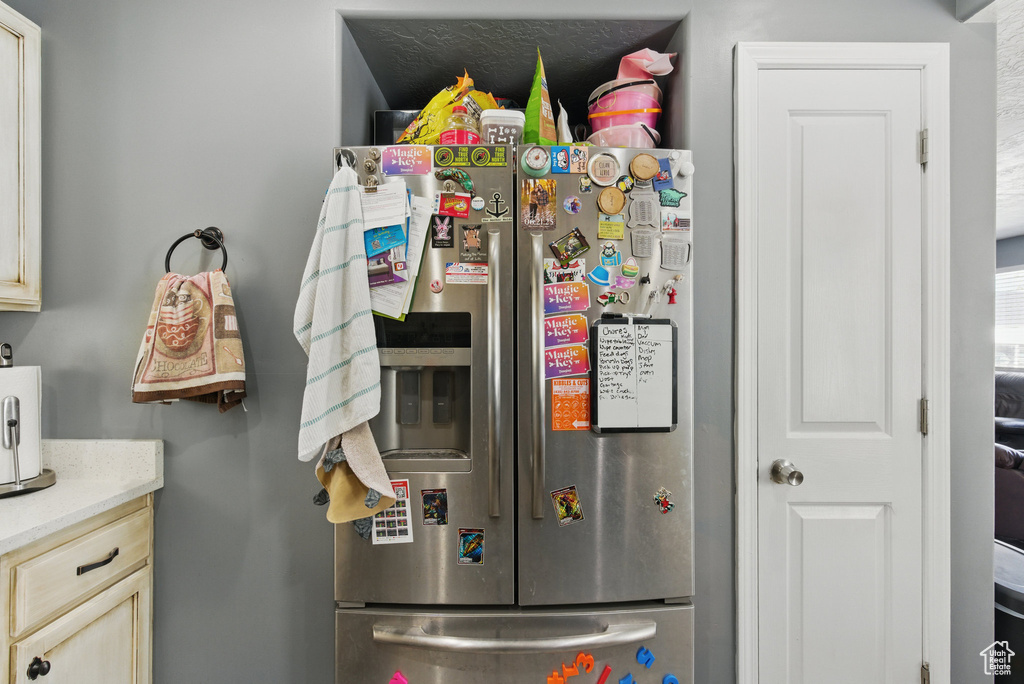 Kitchen with stainless steel refrigerator with ice dispenser and cream cabinetry