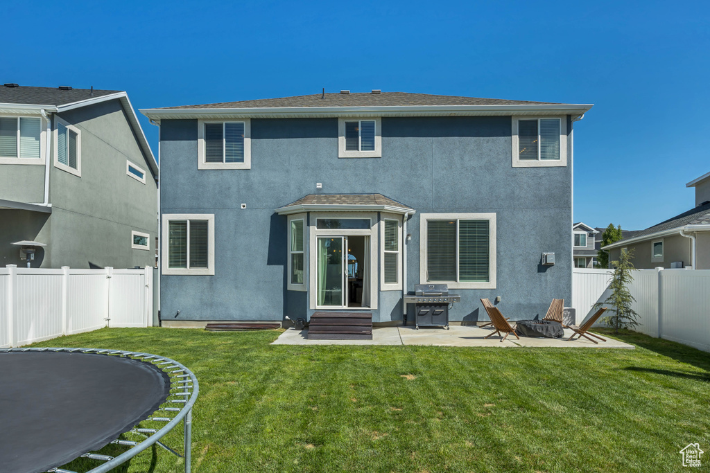 Rear view of property with a trampoline, a patio area, stucco siding, and entry steps