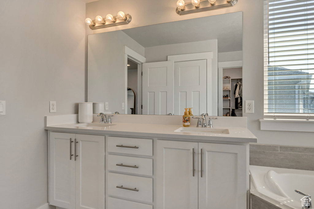 Full bath with double vanity, a garden tub, and a closet