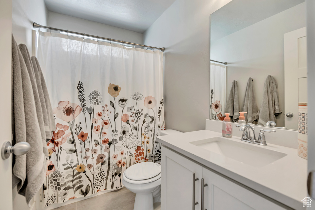 Bathroom with vanity, toilet, a shower with shower curtain, and tile patterned floors
