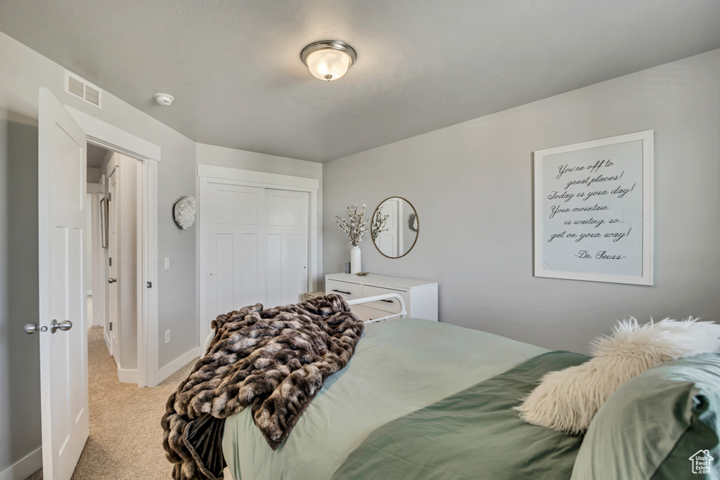 Bedroom featuring light carpet, a closet, and baseboards