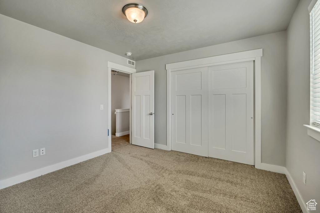 Unfurnished bedroom featuring carpet flooring, baseboards, and a closet