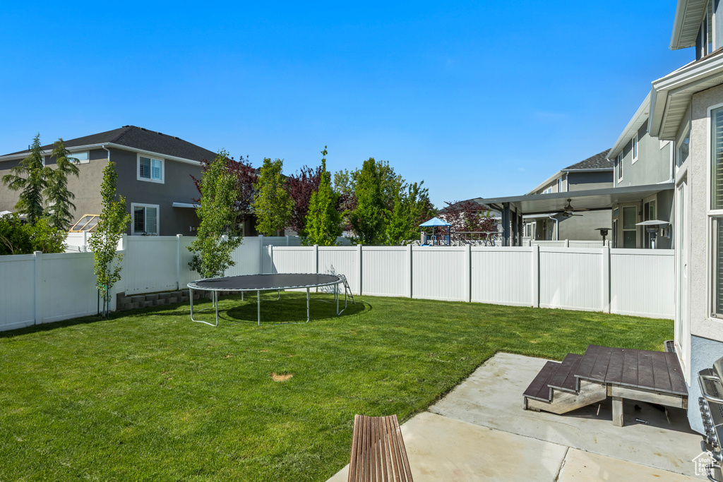 View of yard featuring a ceiling fan, a patio, and a trampoline