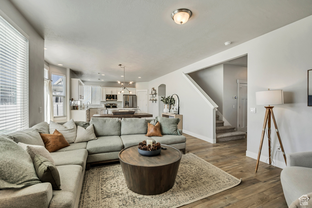 Living room with arched walkways, stairway, wood finished floors, baseboards, and recessed lighting