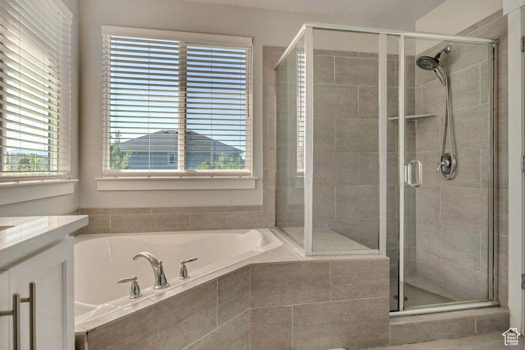 Bathroom featuring vanity, a garden tub, and a shower stall